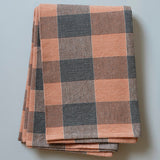 Folded plaid blanket with brown and gray pattern on a light gray background