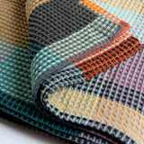 Folded blanket with various patterns and colors on a white background