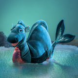 Blue dragon plush toy on a textured surface with a teal background
