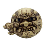 Otafuku demon mask netsuke, or Japanese toggle figurine on a white background