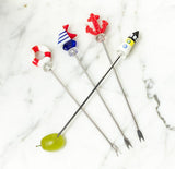 Set of four cocktail skewers with novelty ends on a marble surface