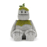 Plush toy resembling a creature with a green scarf and hat on a white background