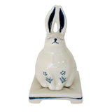 A white ceramic rabbit figurine with blue painted details, sitting on a matching rectangular base against a plain white background.