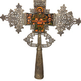 Decorative cross with intricate designs and a figure in the center on a white background
