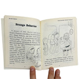 Open book with illustrations and text on Salem witch trials, held by a hand.