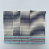 Set of four striped cotton napkins in shades of blue, gray, and beige, handwoven and laid out flat.