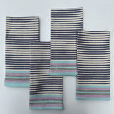 A set of four striped cotton napkins in shades of blue, gray, and beige, handwoven and laid out flat.