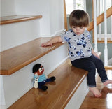 Child sitting on a staircase with a toy sailor figure next to them