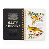 A spiral-bound sticker book titled 'SALTY BIRDS' shown open on a white background. The left page is black with white text, and the right page features colorful bird illustrations and small text labels on a white background.