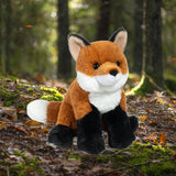 A small plush toy resembling a fox with a brown body, black feet, white markings, and a black nose.