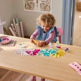 Child playing with colorful building blocks at a table in a room with decorative elements.