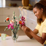 Woman arranging LEGO flowers in a vase on a kitchen counter