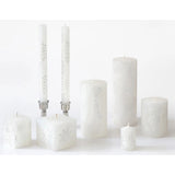 Set of white candles with decorative patterns on a white background