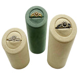 Three cylindrical ring holders in beige and green with rings inside on a white background