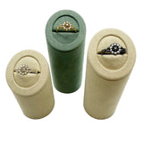 Three cylindrical ring displays in beige and green, with rings inside on a white background