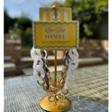 Gold and white chain handle on a stand with a label in an outdoor setting