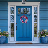 Blue front door with decorative wreath, flanked by flower pots on a blue house exterior.