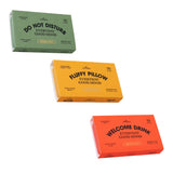 Three rectangular product boxes arranged diagonally on a white background: a sage green box labeled 'DO NOT DISTURB EVERYDAY GOOD MOOD,' a mustard yellow box labeled 'FLUFFY PILLOW EVERYDAY GOOD MOOD,' and a coral red box labeled 'WELCOME DRINK EVERYDAY GOOD MOOD.' The boxes appear to be the products themselves rather than packaging around another visible item.