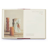 An open book spread showing a styled photo of a fabric wrap tied with a ribbon on the left page, with the text 'POLE-AND-LOOP WRAP' and 'MELA' on the right page.