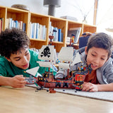 Two children playing with a pirate ship model on the floor.