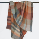 Plaid blanket draped over a rod on a white background