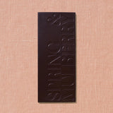 Dark chocolate bar with 'Spring & Mulberry' branding on a beige background