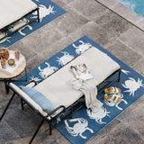 Outdoor lounge chairs on blue crab-patterned rugs by a poolside.
