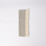 Handwoven placemat in natural and black cotton laid out folded on a white surface.