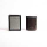 A brown glass jar with a black lid labeled 'FIELD KIT' containing a home candle.