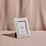 A white marble frame with a rectangular photo placed in the center, standing upright on a neutral background.