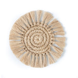 A handwoven, natural fibre coaster in a spiral pattern with fringe edging.