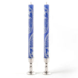 Two blue candles with silver bases on a white background