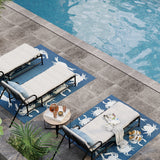 Outdoor seating area by a pool with lounge chairs and a small table on a decorative rug.