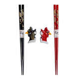 A gift set of chopsticks and rests with a gold dragon design on a red and black background.