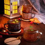 Decorative glass mugs with tea on a wooden table with a lantern in the background