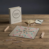 Scrabble game set up on a wooden table with tiles and board visible