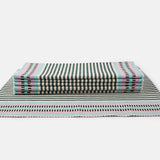 A set of handwoven placemats featuring a striped pattern in beige, pink, green, and blue.