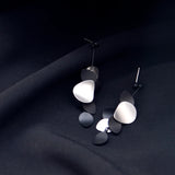 Pair of modern earrings on a dark fabric background