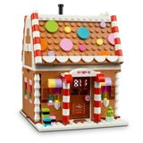 A LEGO gingerbread house building set photographed on a clean white background. The structure has a brown facade, white trim, red-and-white striped candy cane posts, colorful circular roof decorations, and small multicolored window and decor accents.