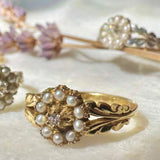 Gold ring with pearls on a white surface with blurred jewelry in the background