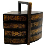 Decorative black and gold tiered box with handle on a white background