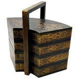 Decorative black and gold tiered box with handle on a white background