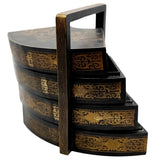 Stack of black and gold decorative trays with a handle on a white background