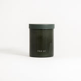 A green glass jar labeled 'FIELD KIT' containing a candle.