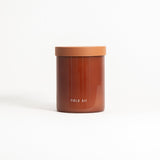 A glass jar with a lid labeled 'FIELD KIT' containing a brown-colored candle.