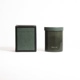 A green glass jar with a green lid labeled 'FIELD KIT' containing a home candle.