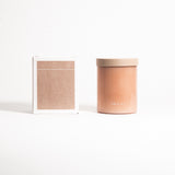 A beige, cylindrical glass jar with a lid labeled 'FIELD KIT' containing a candle.