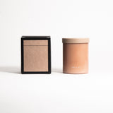 A beige glass jar with a tan lid labeled 'FIELD KIT' containing a home candle.