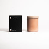 A beige glass jar with a tan lid labeled 'FIELD KIT' containing a home candle.