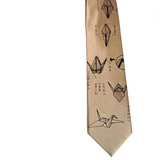 A beige silk necktie featuring a black origami crane pattern with Japanese calligraphy, shown against a plain white background.